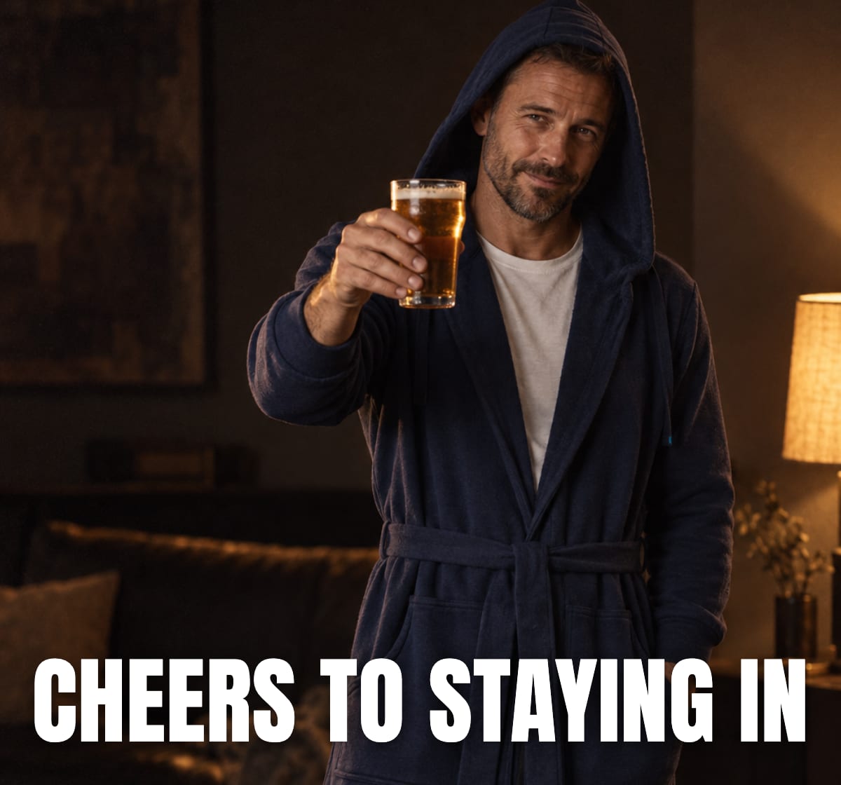 Man in a navy DudeRobe raising a beer, cheers to staying in