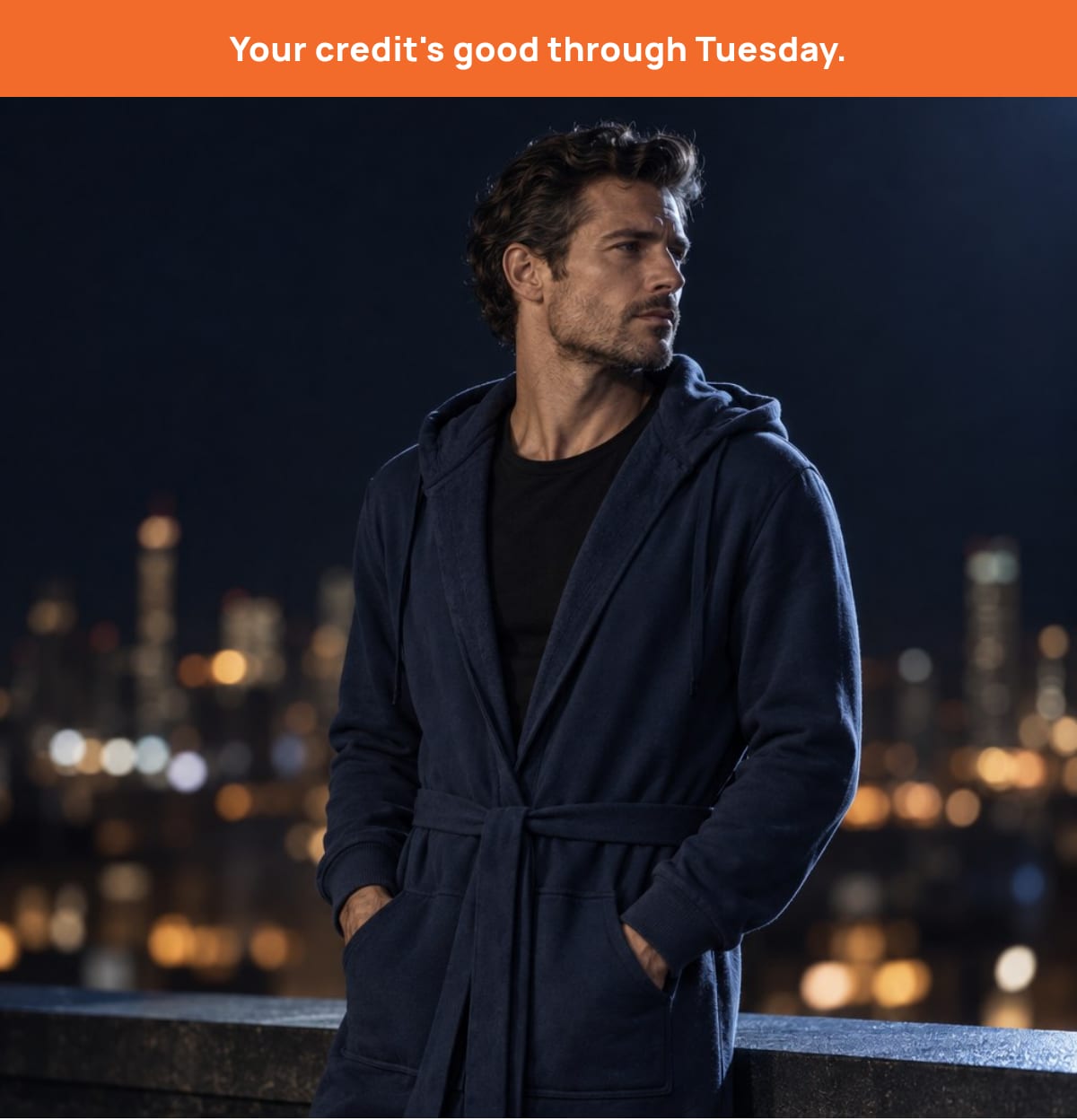 Man in a navy DudeRobe at night with the city lights behind him